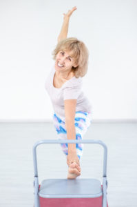 Decorative Image: Smiling senior woman doing yoga with chair at home. Stretching exercises.
