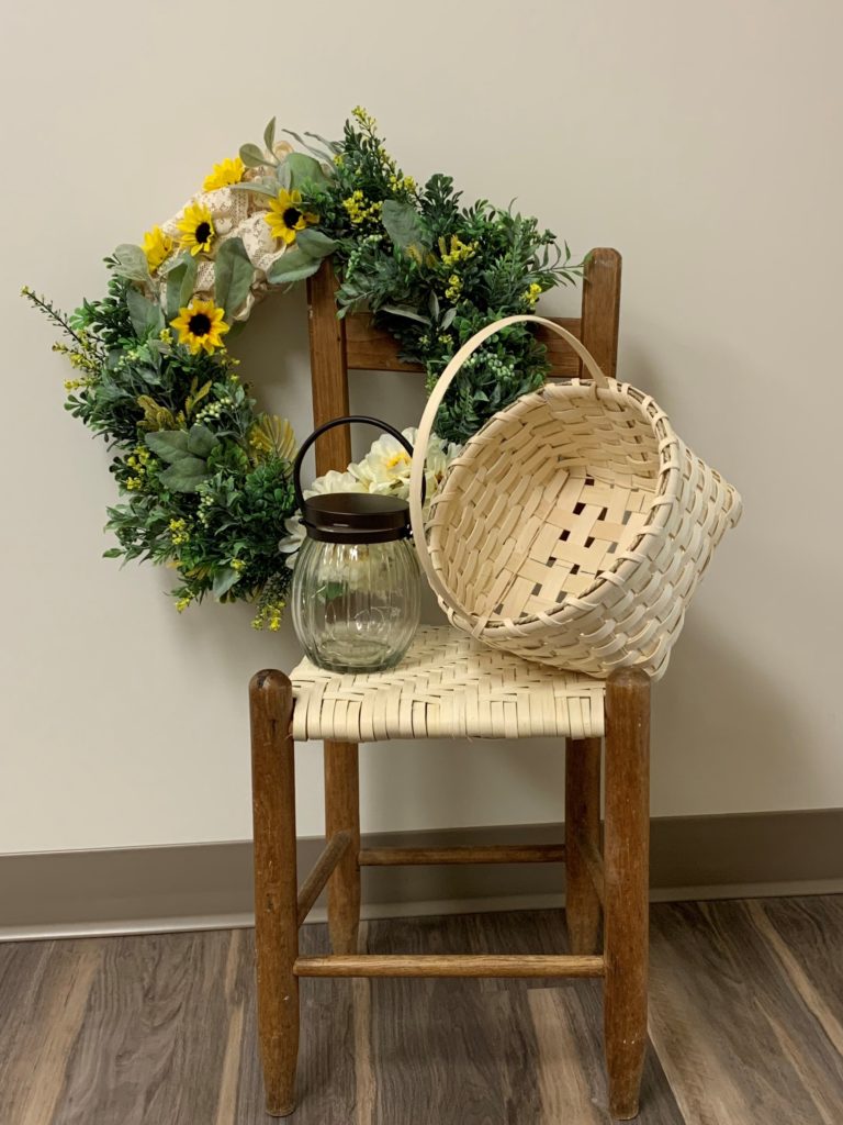 child's chair staged with a handwoven basket, a handmade wreath and a small lantern