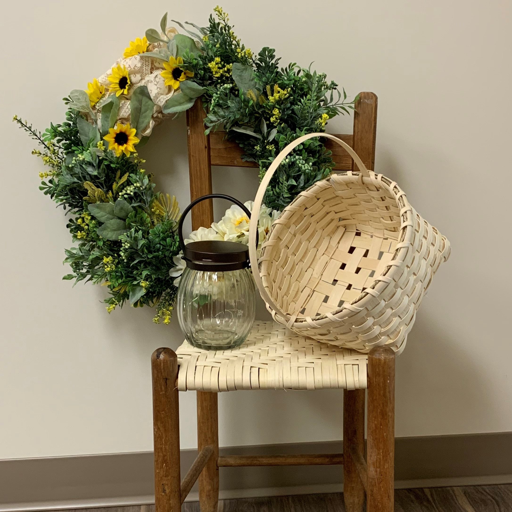 child's chair staged with a handwoven basket, a handmade wreath and a small lantern 