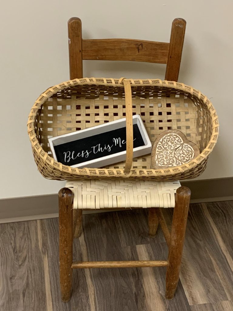 child's chair with an image of a basket holding a wooden heart jewelry box and a small chalkboard sign that says bless this mess.