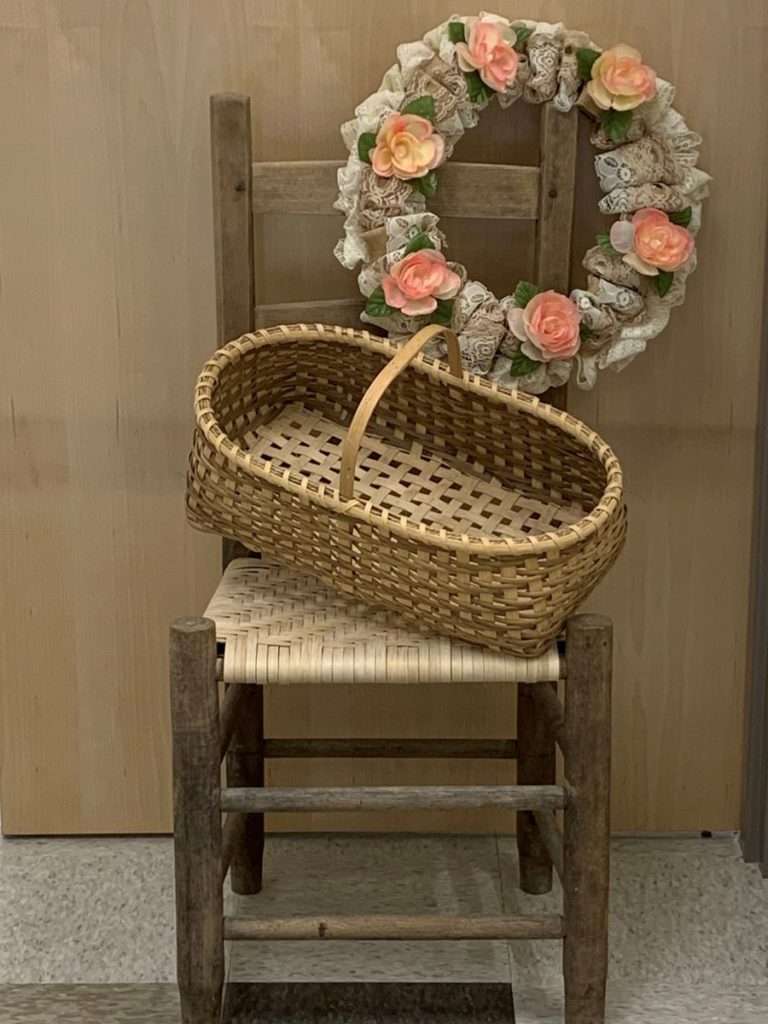 chair with a handwoven basket and a lace wreath with pink flowers