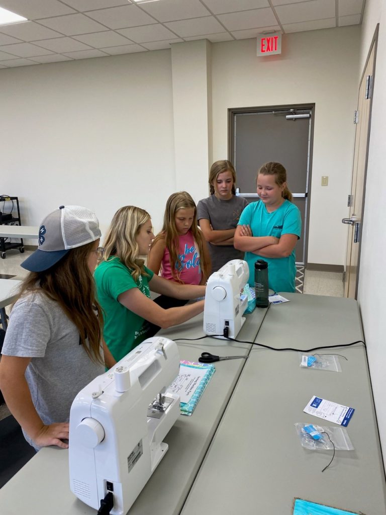 Students being instructed on how to use a sewing machine