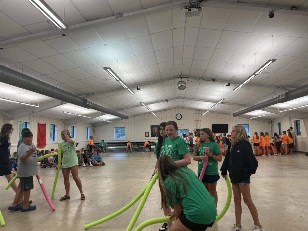 Students playing with pool noodles in the gym