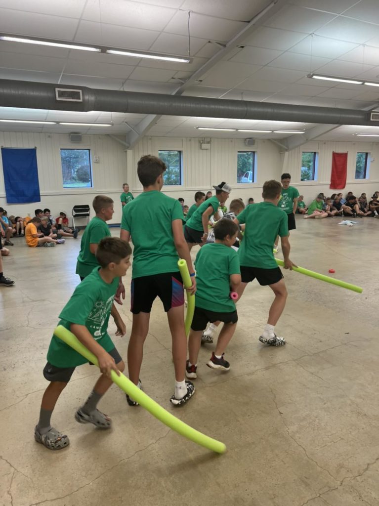 Students playing with pool noodles in the gym