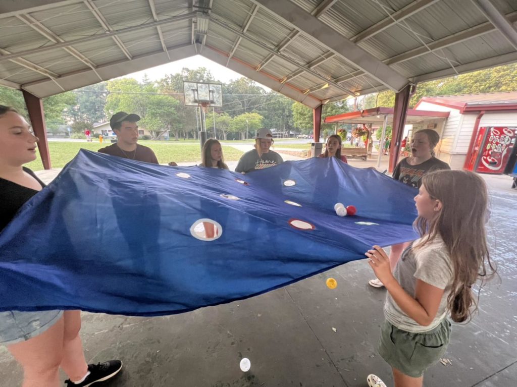 Children playing a game with a blue tarp.