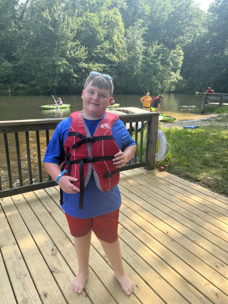 Student in Life Jacket with Kayaks behind