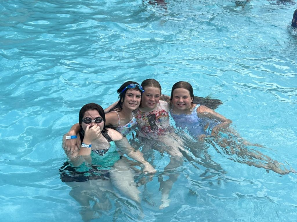 Four girls hugging in the swimming pool