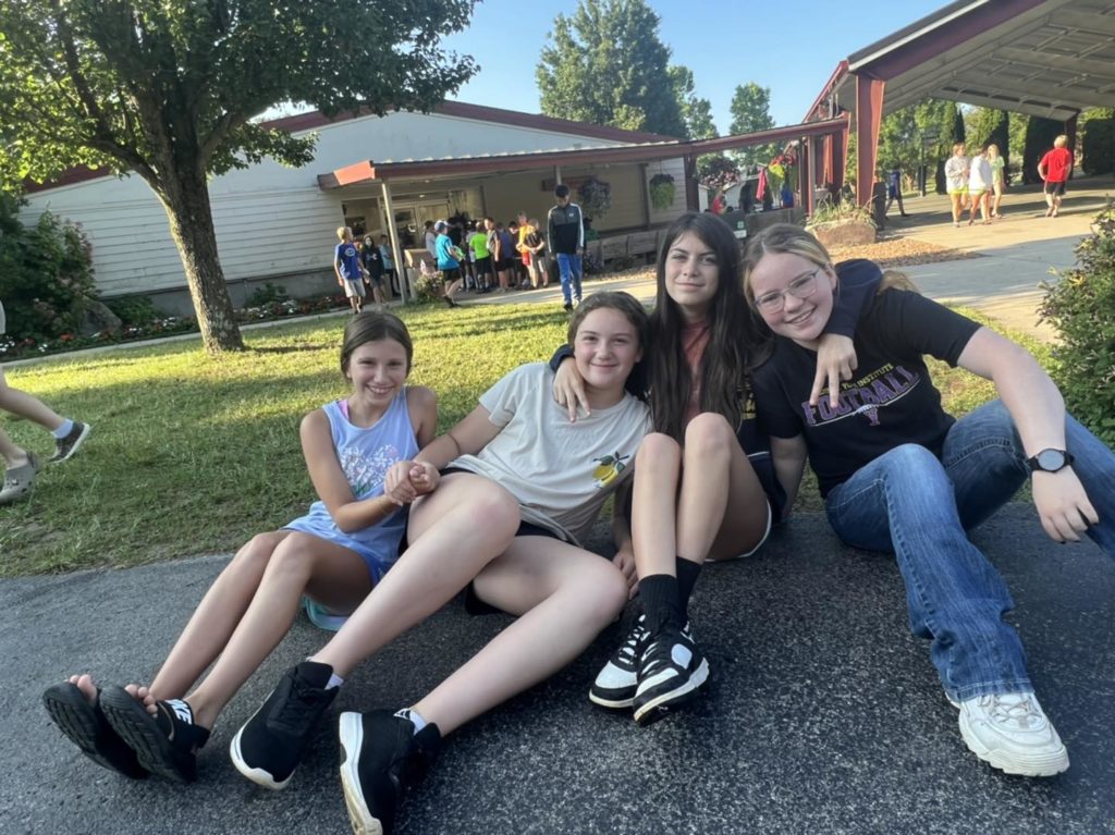 group of friends sitting on the pavement at 4-H camp